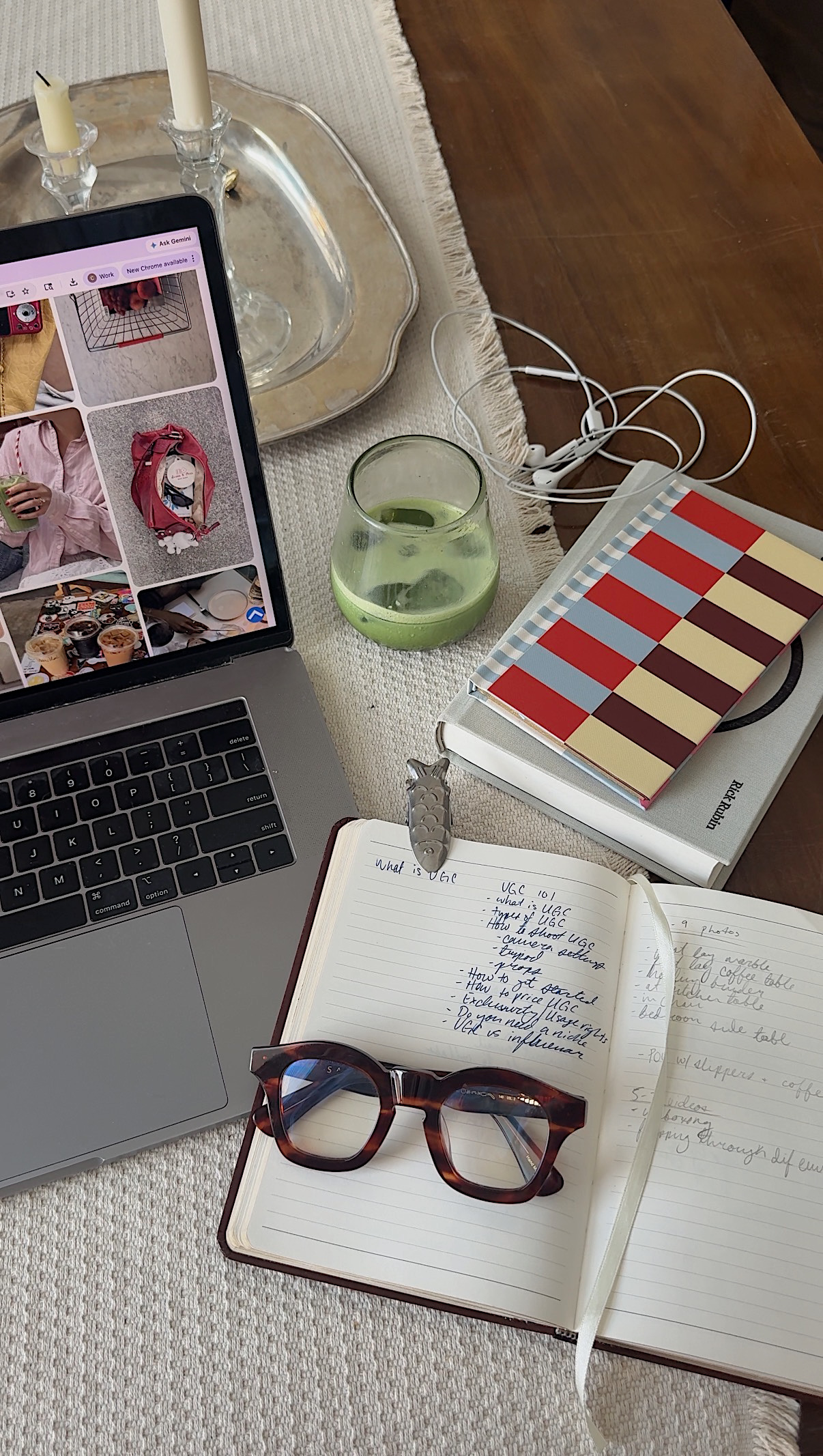 A laptop, candles and a notebook on a warm-lit desk